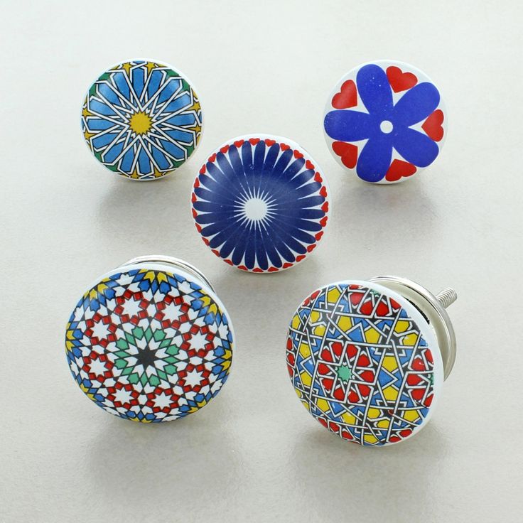 four different colored knobs with designs on them sitting next to each other in front of a white background