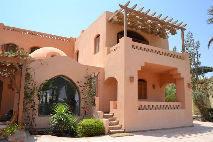 a large pink house with lots of greenery on the front