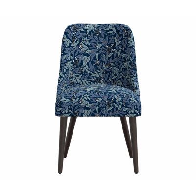 an upholstered blue chair with wooden legs and a leaf pattern on the back