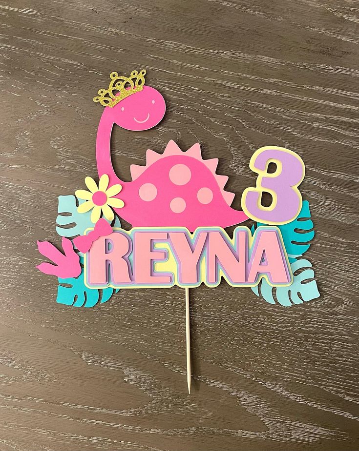 a birthday cake topper with the number 8 on it and a pink dinosaur holding a flower