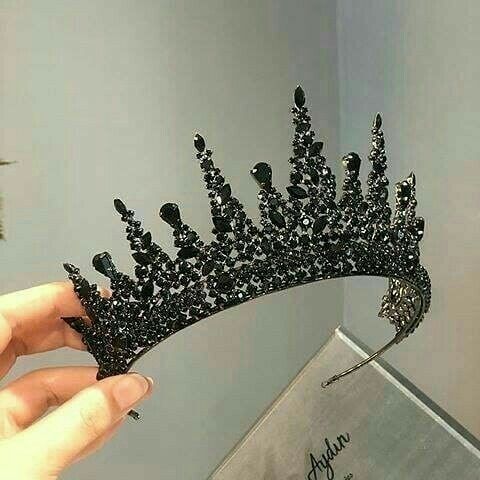 a hand holding a black tiara in front of a mirror