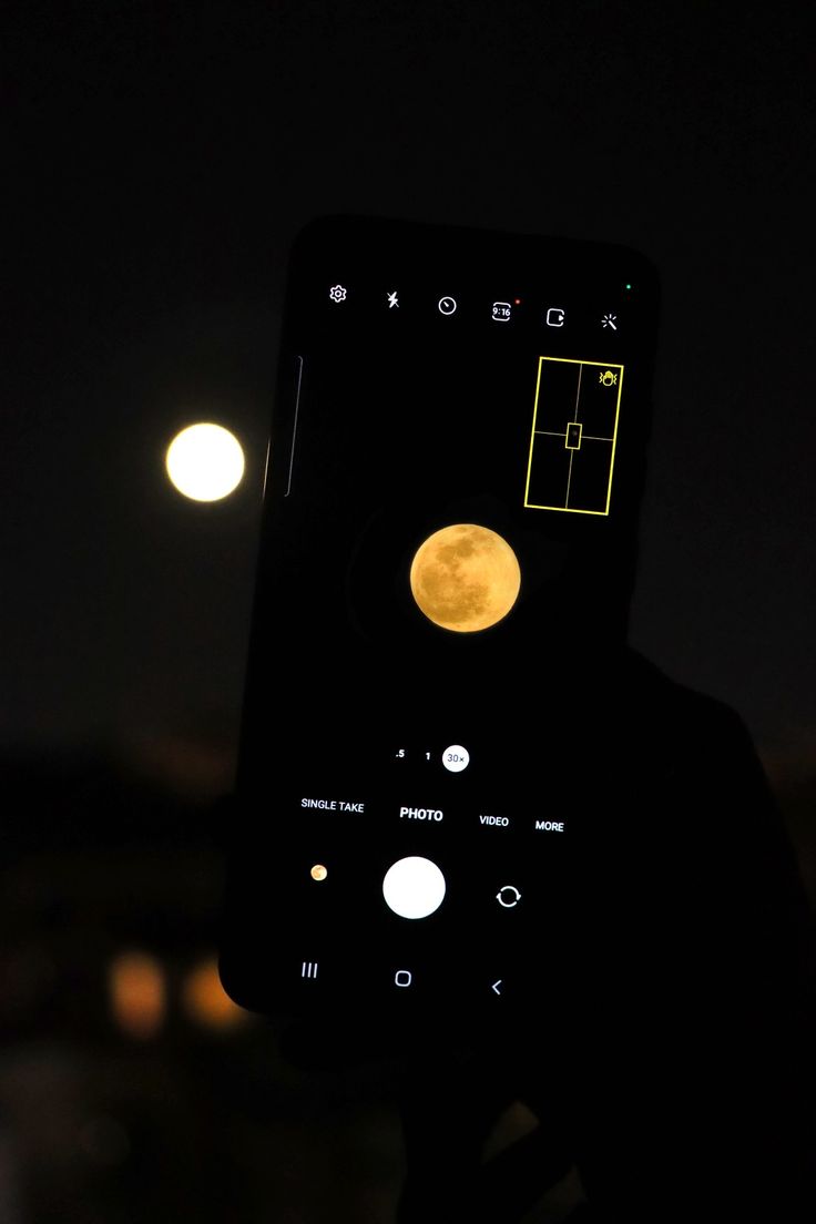 someone holding up their cell phone with the moon in the background