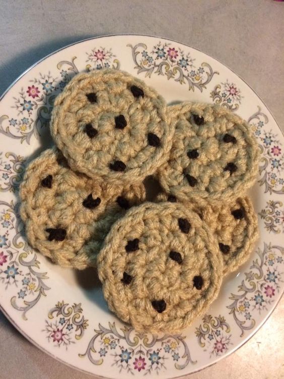 four crocheted cookies sitting on top of a white plate