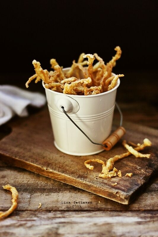 a white bucket filled with fried food on top of a wooden cutting board