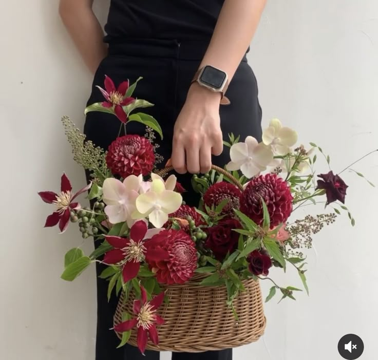 a person holding a basket with flowers in it