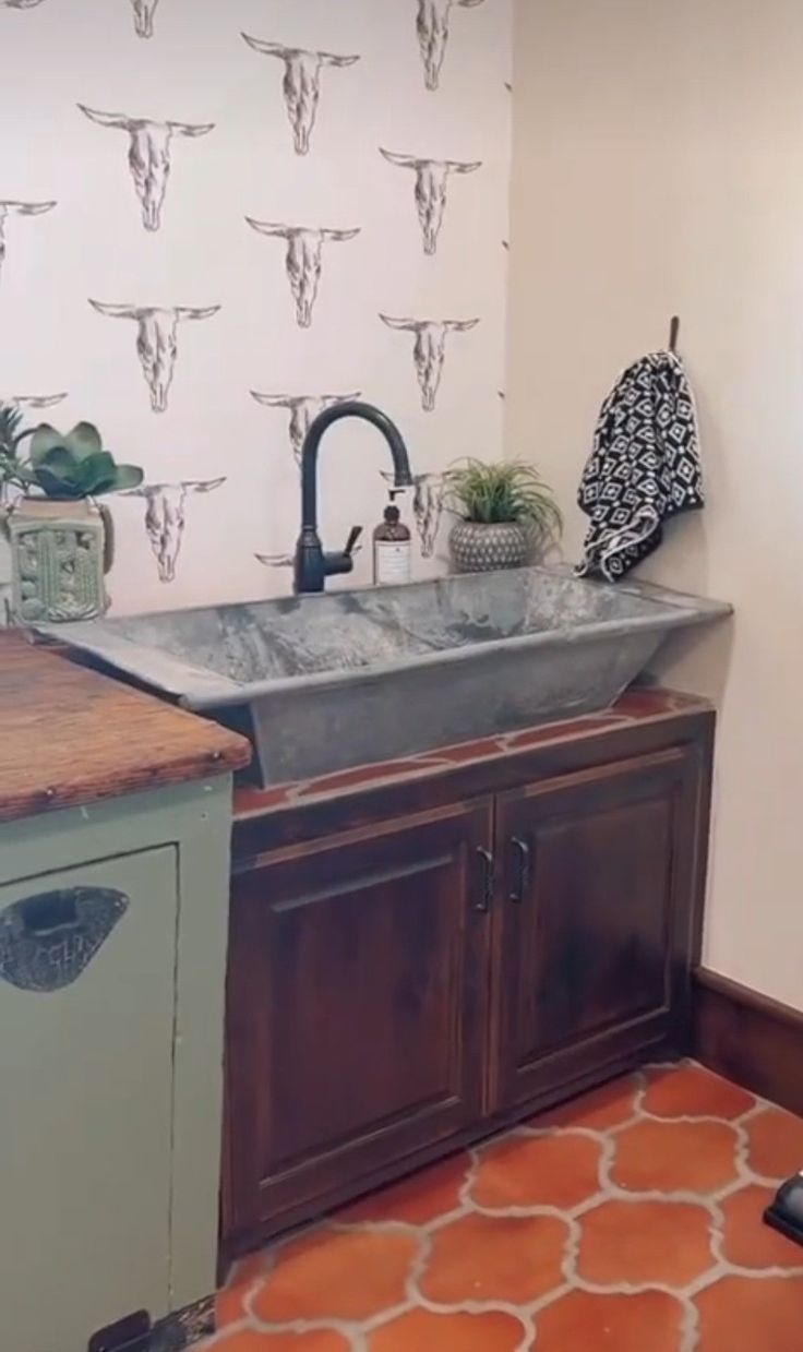 a kitchen with a sink, counter top and wallpaper in the backround