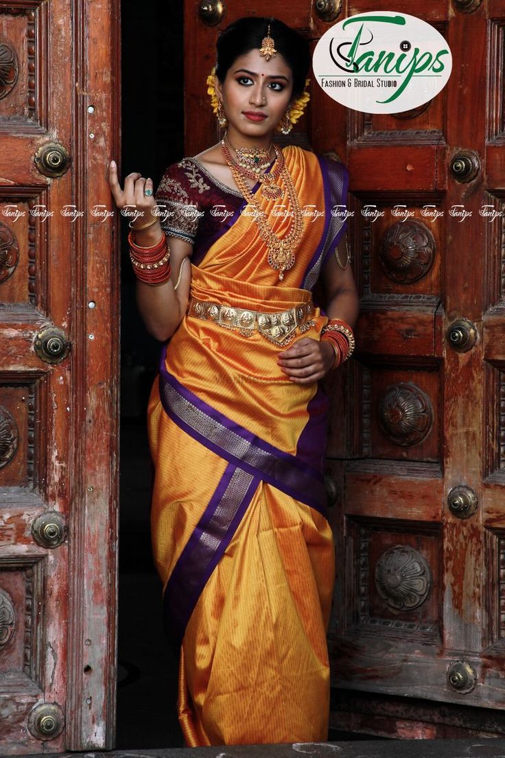 a woman in an orange and purple sari is standing at the entrance to a building