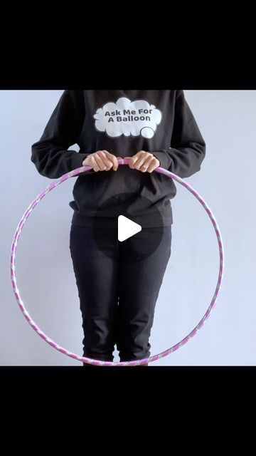 a woman holding a pink hula hoop in her hands while wearing a black sweatshirt