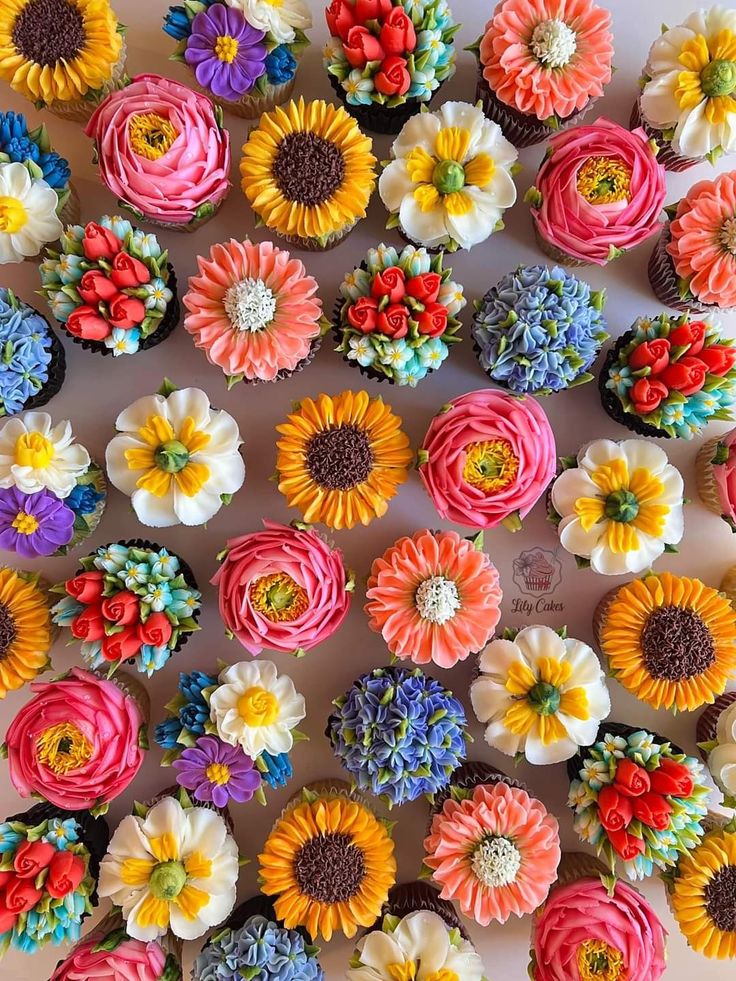 cupcakes decorated with colorful flowers are arranged on a table top for a celebration