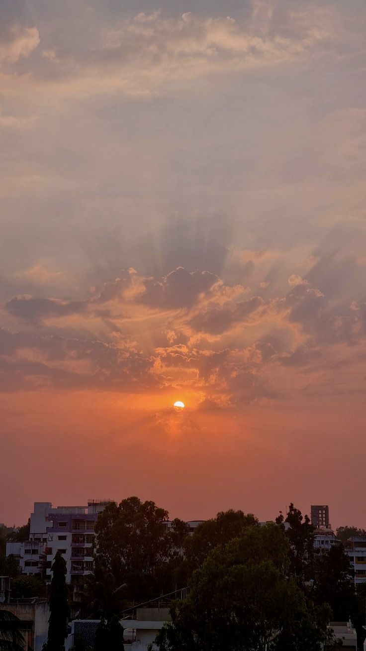 the sun is setting over some buildings and trees