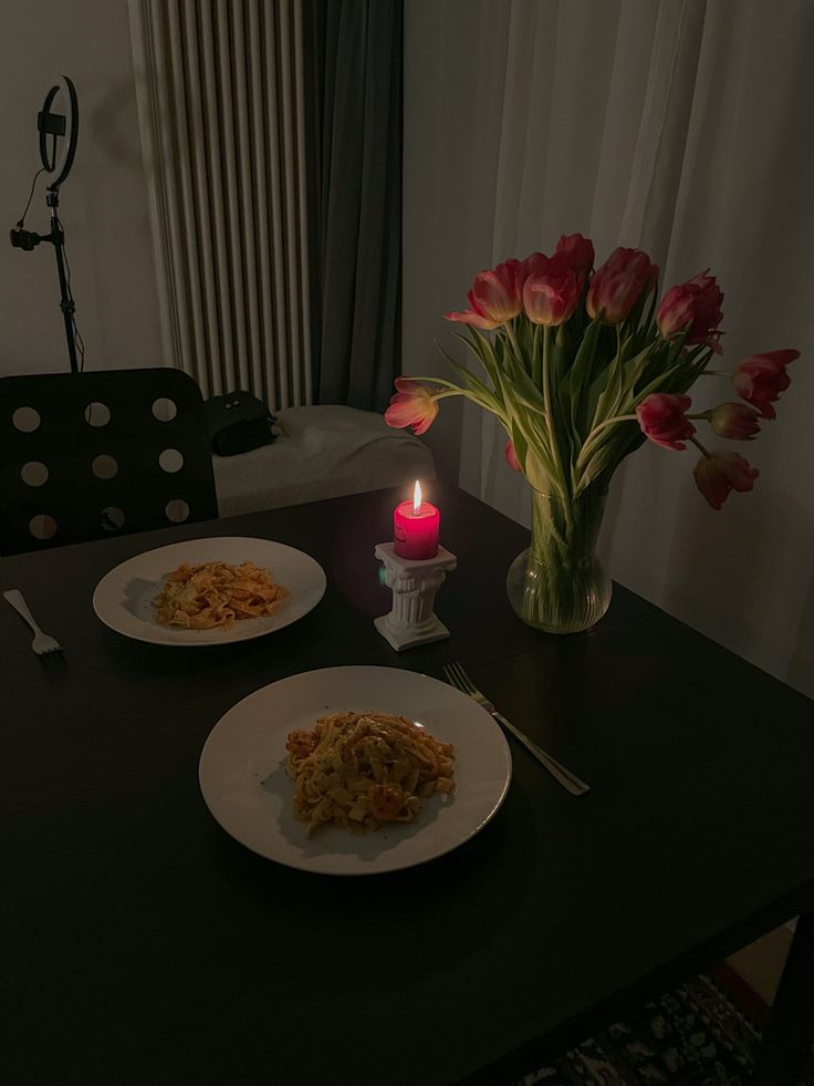 the table is set with two plates of food and a lit candle on top of it