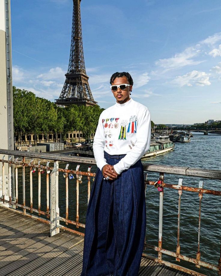 a man standing in front of the eiffel tower with his hands on his hips