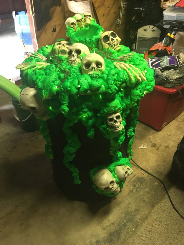 a bunch of fake skulls sitting on top of a trash can filled with green stuff