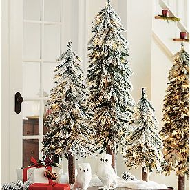 two white owls sitting on a table in front of christmas trees