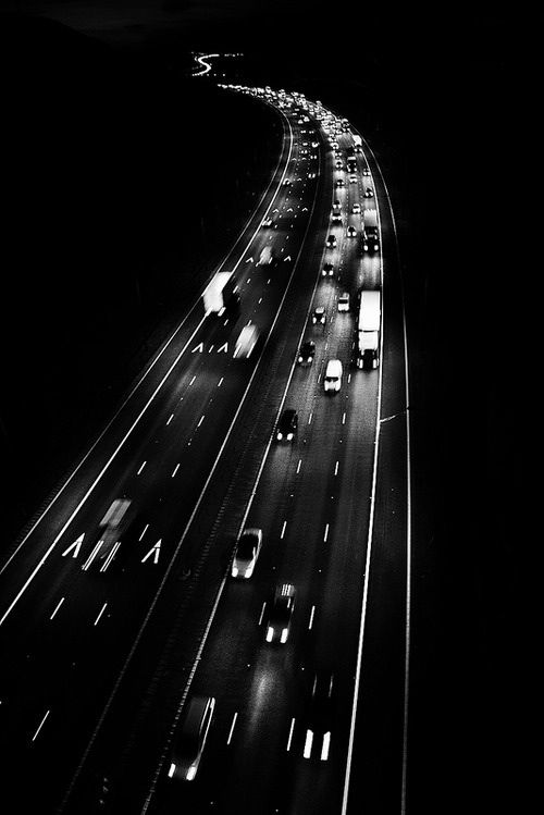 black and white photograph of traffic on highway at night