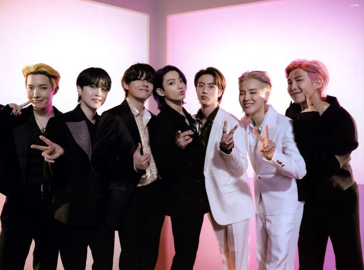 group of young men standing next to each other in front of a pink and white wall