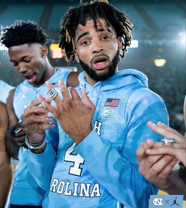 two men in blue jerseys standing next to each other with their hands up and one man holding