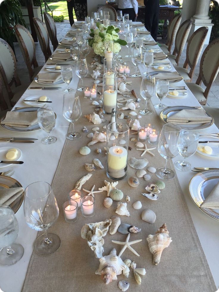 a long table is set with candles and seashells