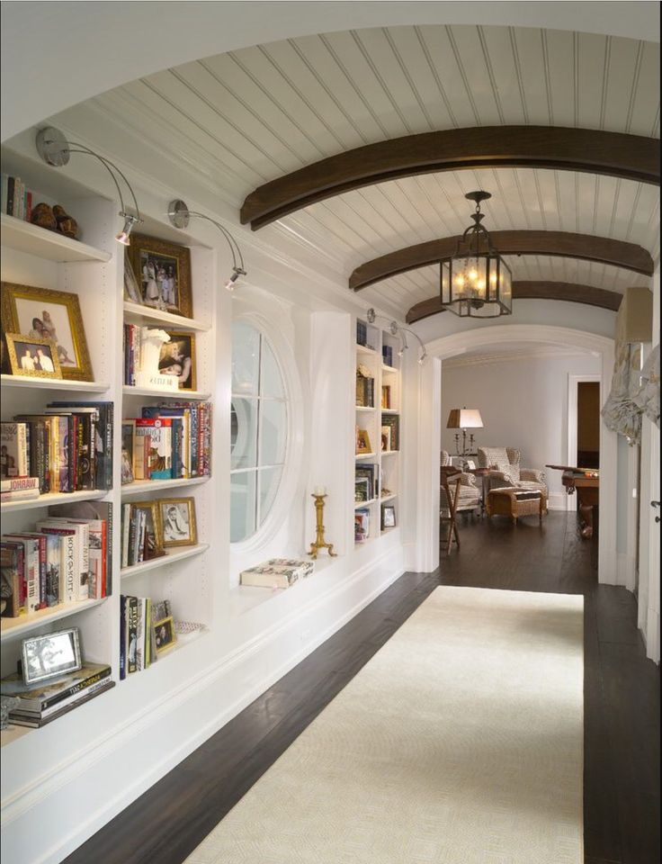 a long hallway with bookshelves filled with lots of books next to a doorway