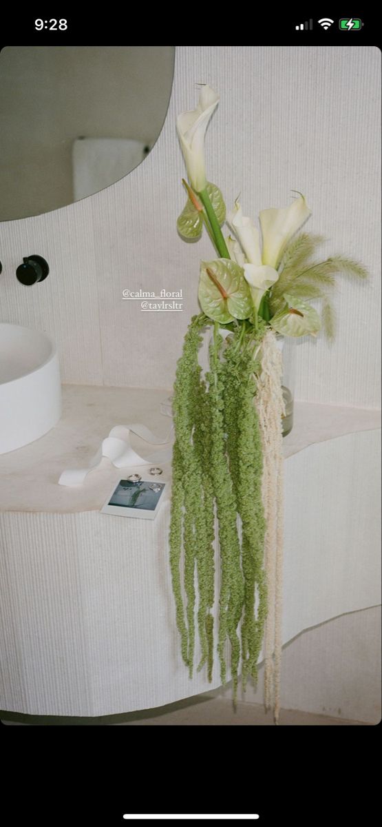 a vase filled with white flowers sitting on top of a table next to a mirror