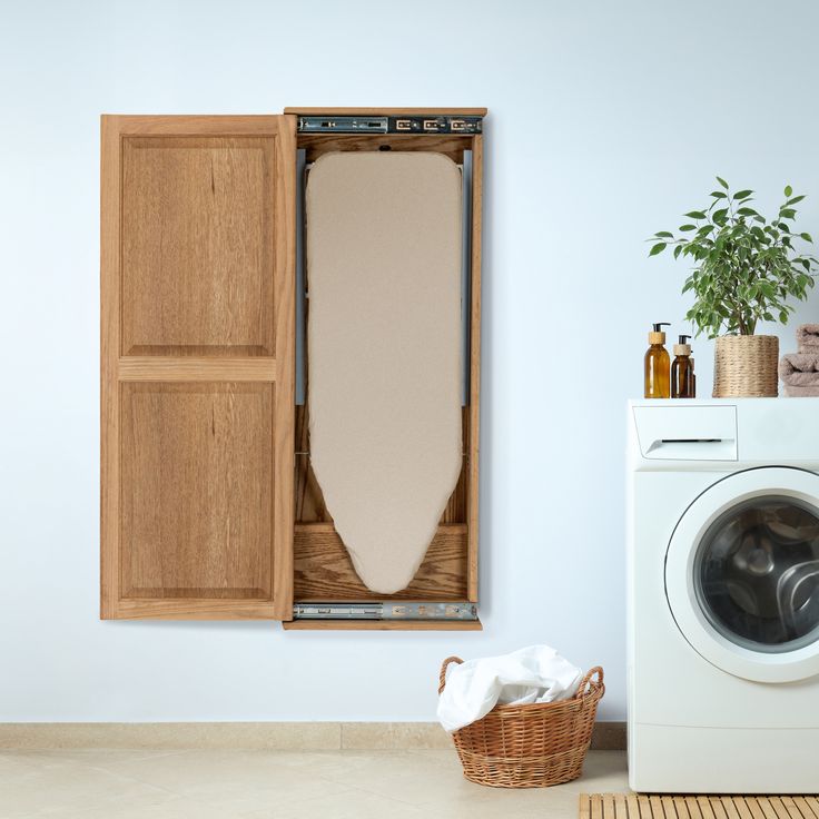 a washer and dryer sitting in front of a wooden cabinet with an ironing board