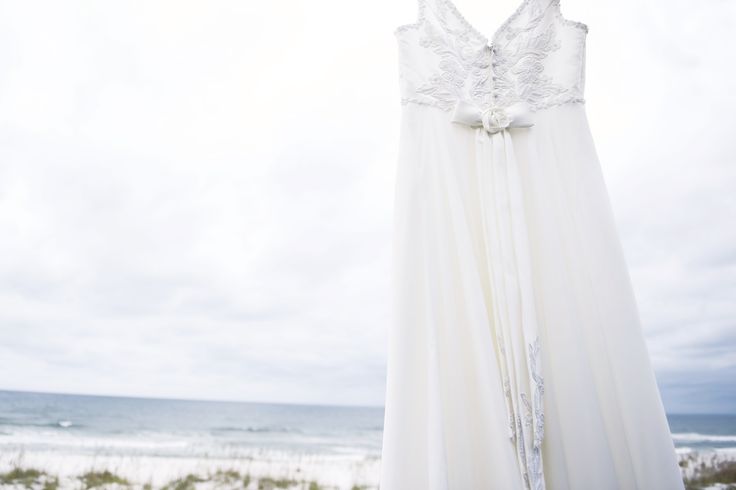 a wedding dress hanging on a clothesline at the beach