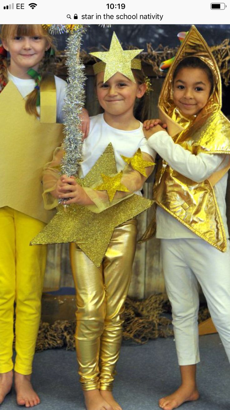 three young children dressed up in gold and white outfits, one is holding a star