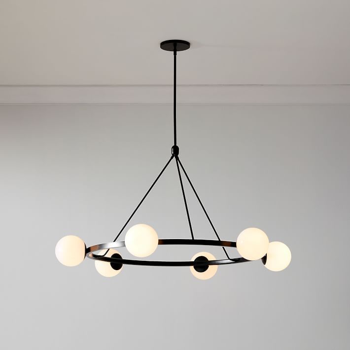 a black chandelier with five lights hanging from it's center and four white balls on the bottom