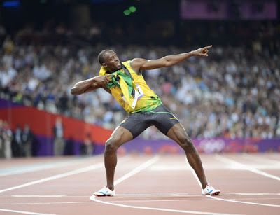 a man in a yellow shirt and black shorts on a track with his arms outstretched