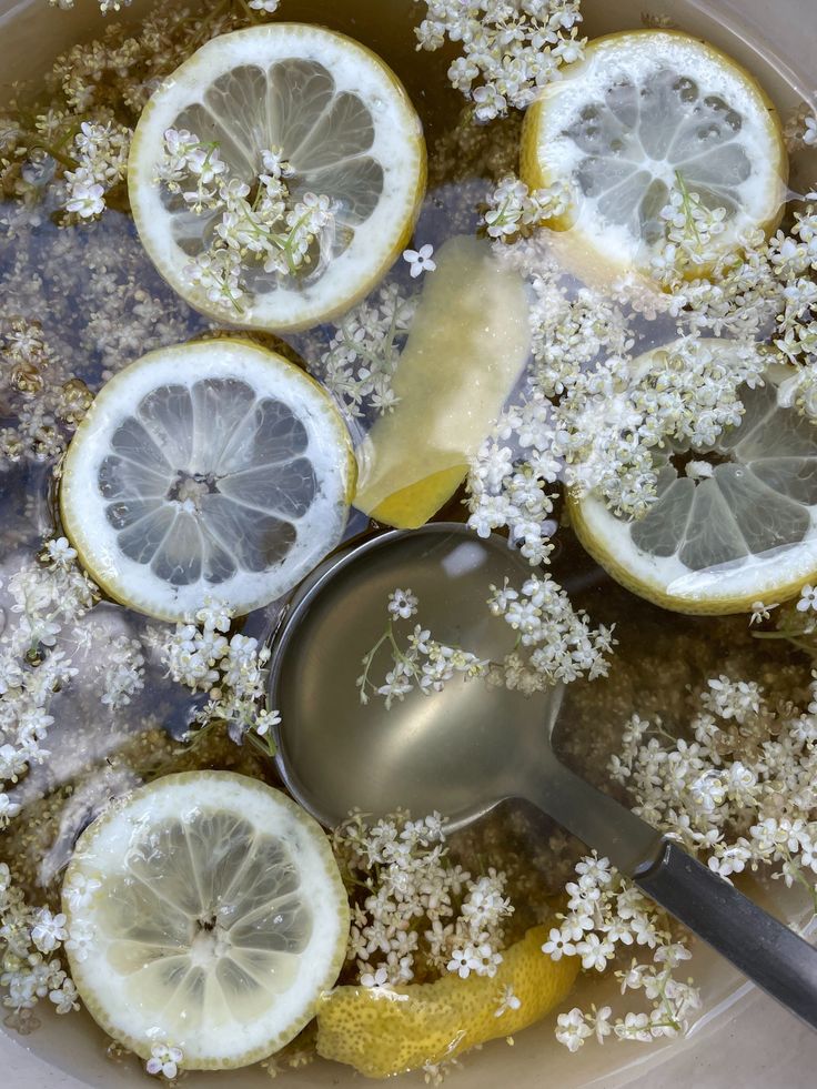 lemons and flowers in a bowl with a spoon