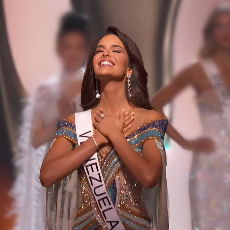 a woman in a dress smiles as she stands with her hands on her chest