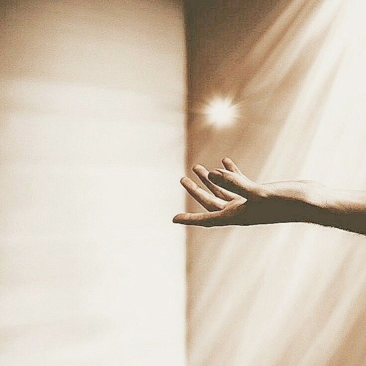 a person's hand reaching out towards the light