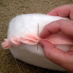 someone is sewing something on top of a piece of white material with pink thread in it