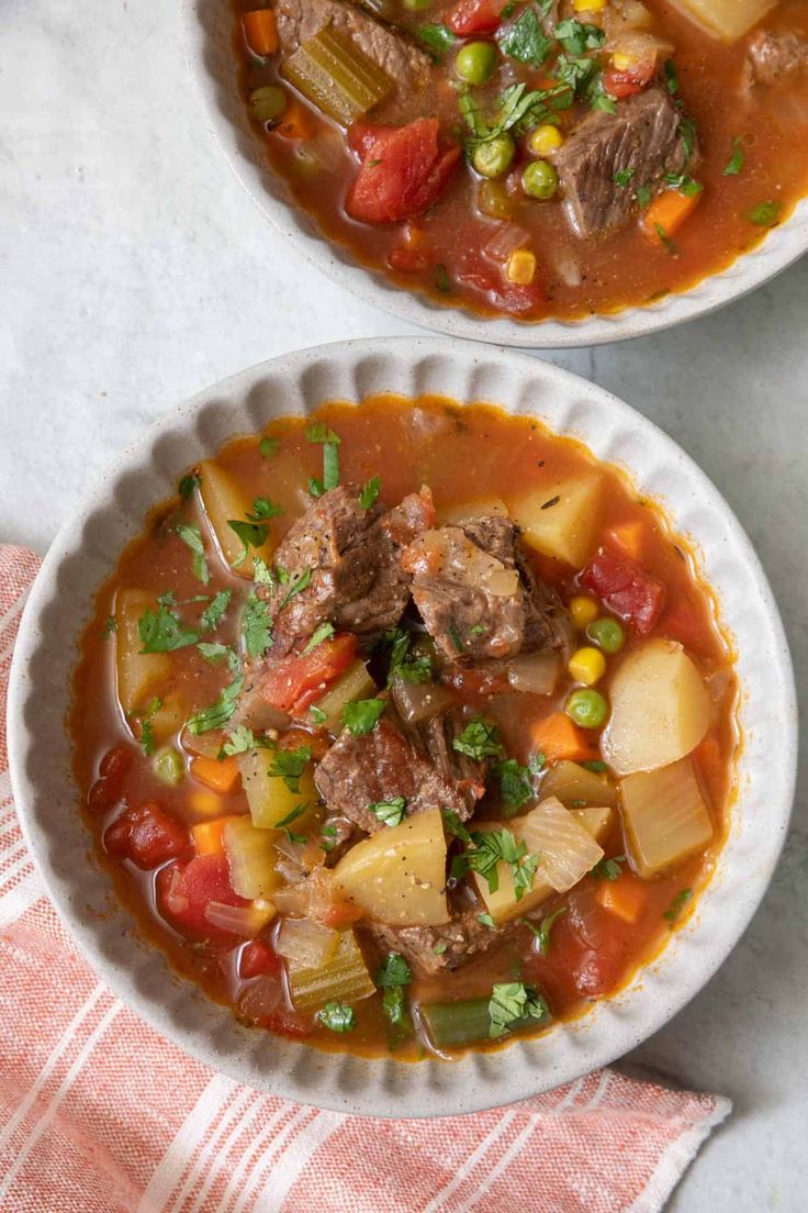 two white bowls filled with meat and vegetable soup