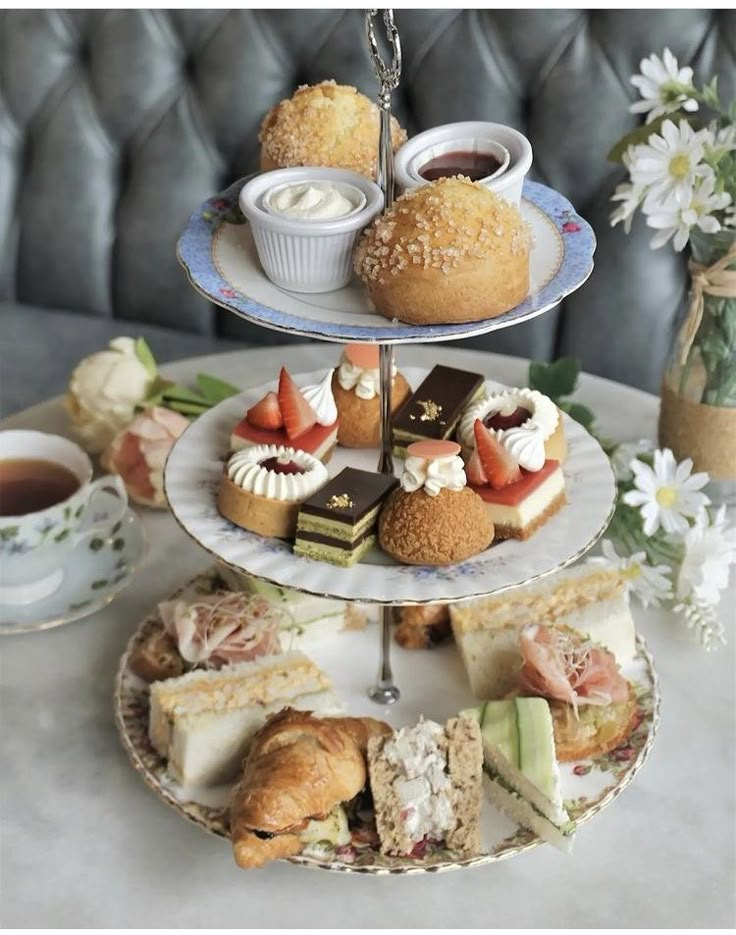 three tiered trays filled with pastries and desserts on top of a table