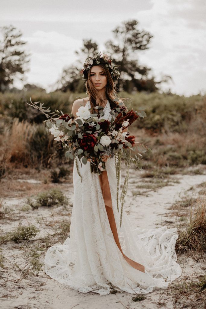 a woman standing in the sand holding a bouquet