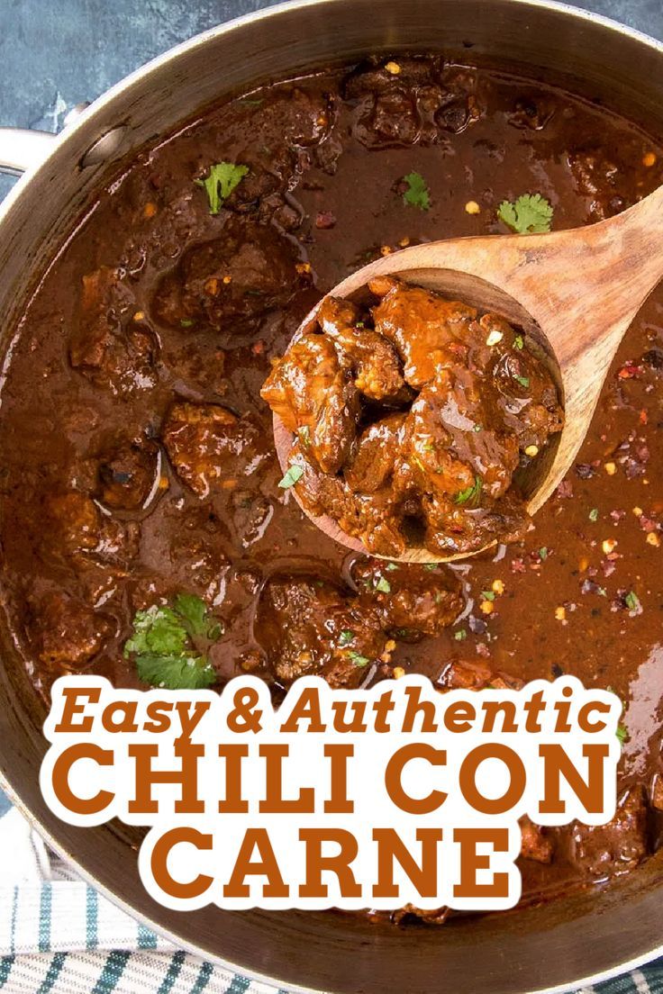 a wooden spoon in a pot filled with chili con carne