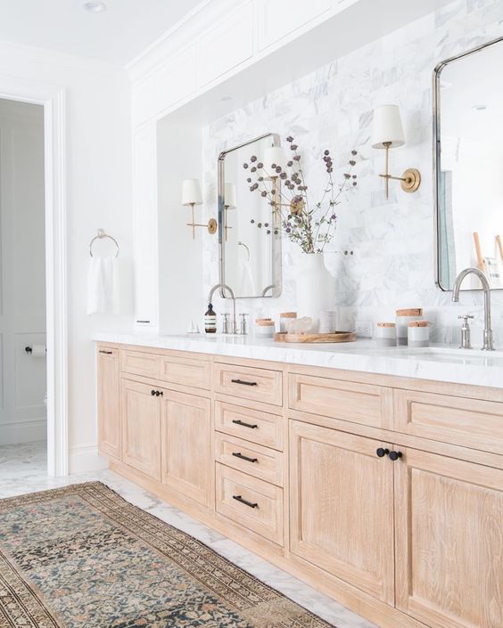 a bathroom with marble counter tops and wooden cabinets, along with a rug on the floor