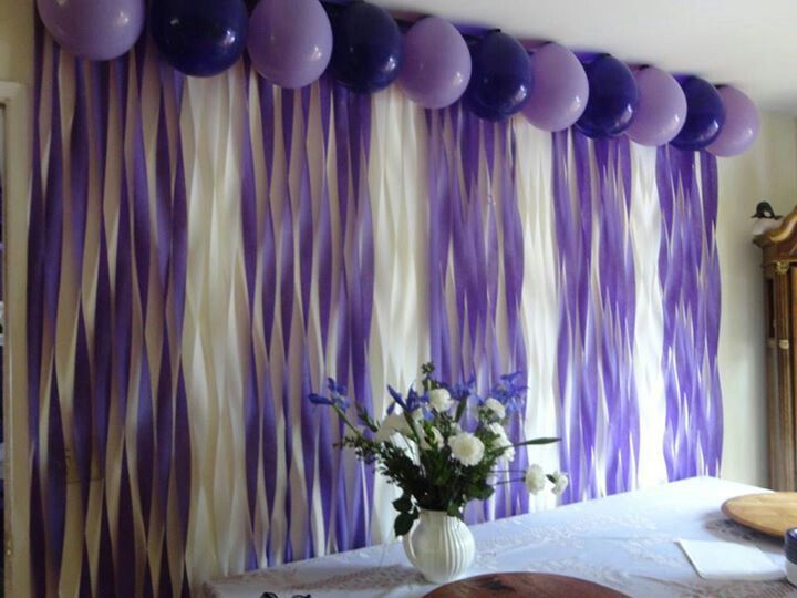 purple and white balloons are hanging on the wall in front of a dining room table