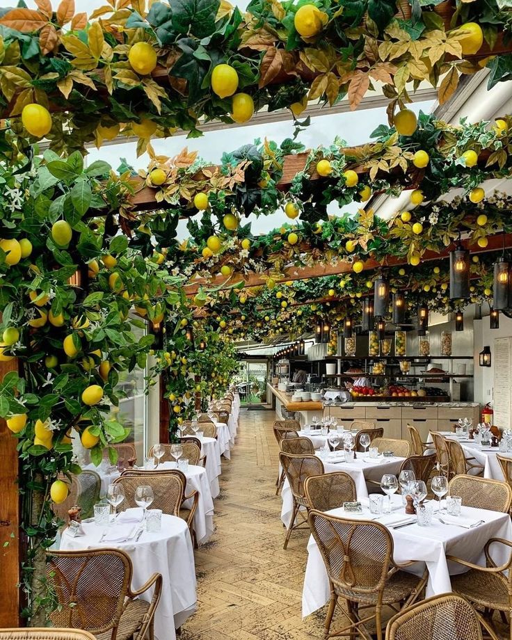 an indoor dining area with tables and chairs covered in lemons hanging from the ceiling