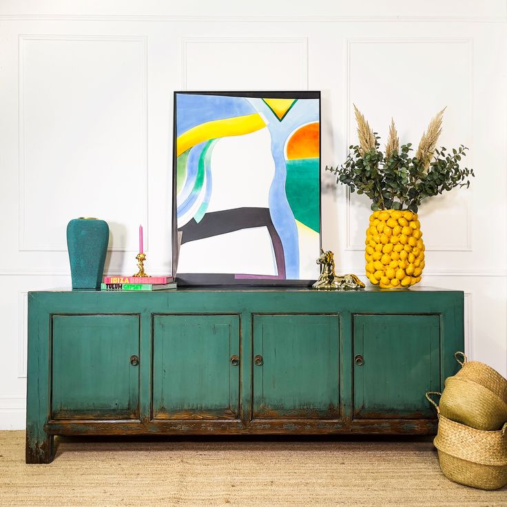 a green cabinet sitting in front of a painting on the wall