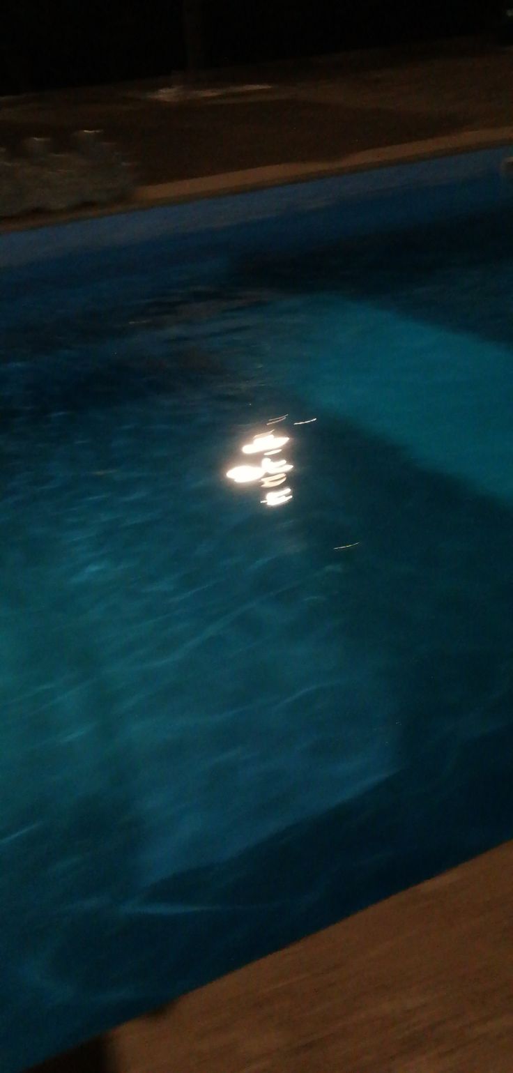 an empty swimming pool at night with the moon in the sky and water reflecting on the surface