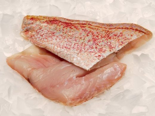 two pieces of raw fish sitting on top of ice covered in red and white sprinkles