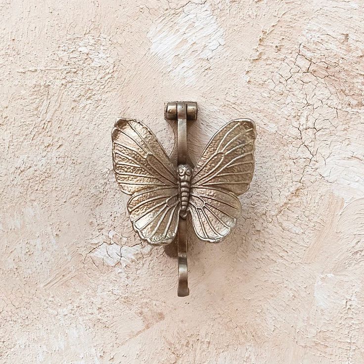 a butterfly shaped metal object mounted to the side of a wall