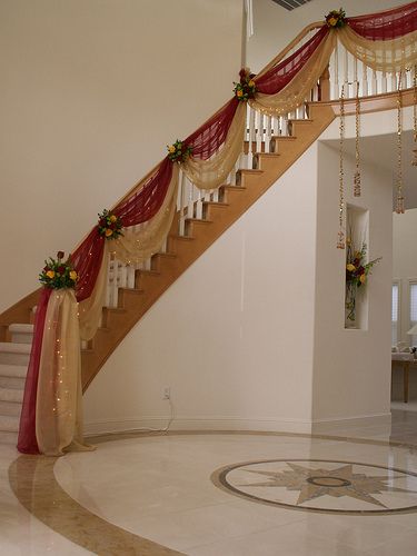 the stairs are decorated with red and gold ribbons, flowers and garlands on them