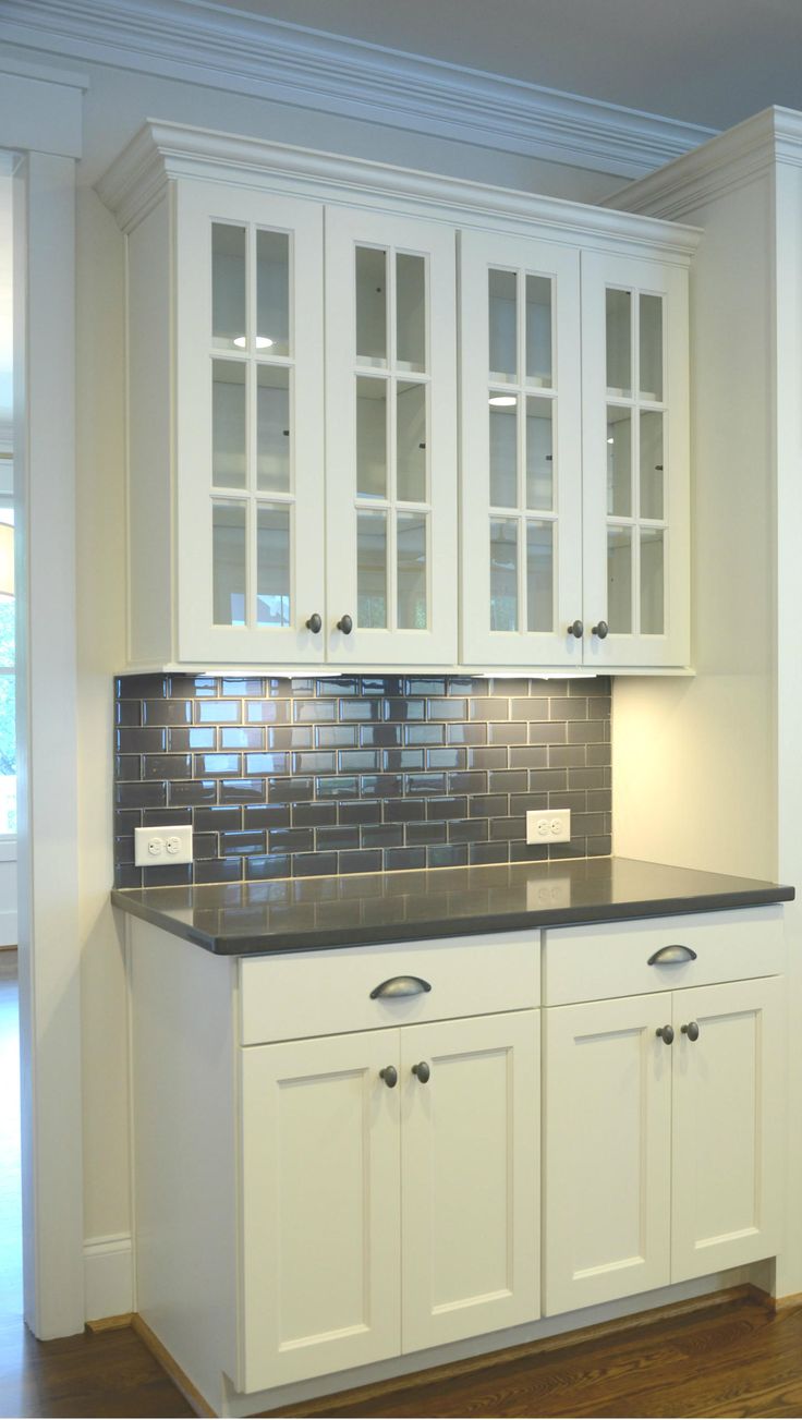 an empty kitchen with white cabinets and black counter tops, along with hardwood floors in the background