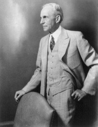 an old black and white photo of a man in a suit holding a guitar case