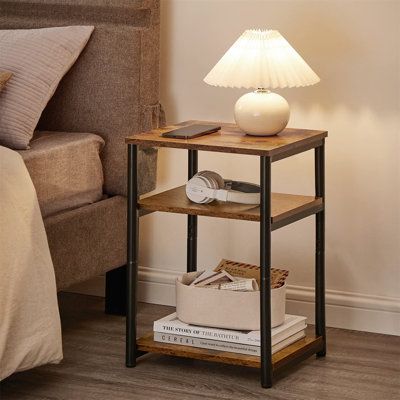 a nightstand with a lamp on it next to a bed