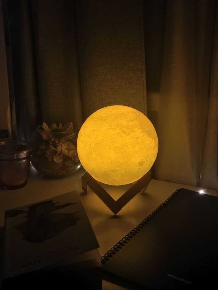 a yellow light sitting on top of a table next to a laptop computer and notebook