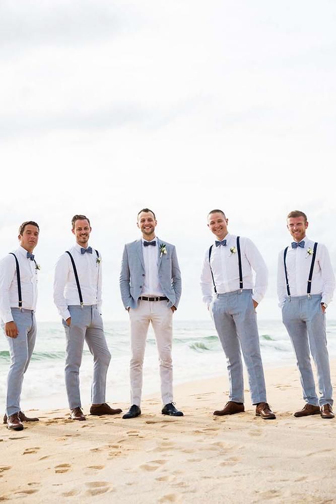 a group of men standing next to each other on top of a sand covered beach